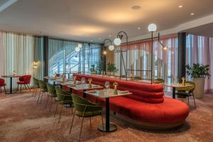 a restaurant with a red couch and tables and chairs at Hilton Paris La Défense in Puteaux
