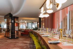 a restaurant with long tables and green chairs at Hilton Paris La Défense in Puteaux
