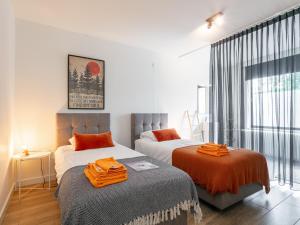 a bedroom with two beds with orange pillows on them at Maison Clement in Maasmechelen
