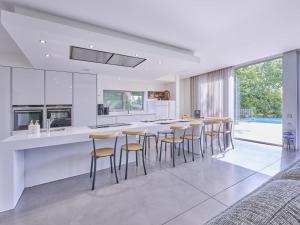a white kitchen with a bar with stools in it at Maison Oscar in Tongeren