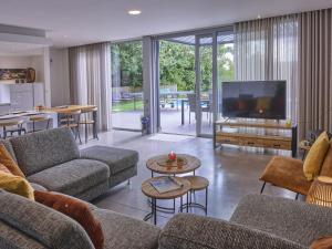 a living room with couches and a large screen tv at Maison Oscar in Tongeren