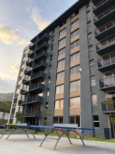 a large apartment building with two benches in front of it at Modern top floor apartment with pool in San Marcos