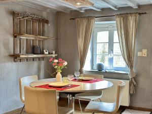 a dining room with a table and chairs and a window at Le Fournil in Manhay