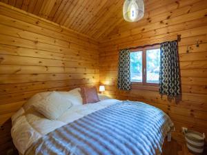 ein Schlafzimmer mit einem Bett in einer Blockhütte in der Unterkunft lOrée in Biron