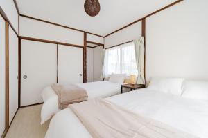 two beds in a room with two windows at Tsuga1976 in Chiba