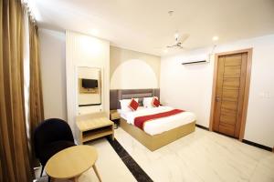 a bedroom with a bed and a table and a chair at Hotel Ember in Alwar
