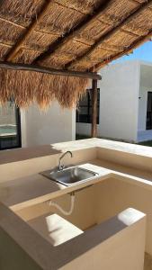 a kitchen with a sink under a straw roof at Casa Nahox in Hunucmá