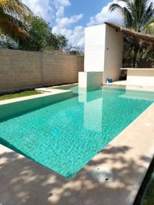 a swimming pool with blue water in front of a house at Casa Nahox in Hunucmá