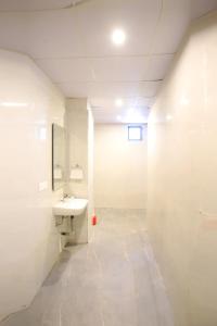 a white bathroom with a sink and a mirror at Hotel Ember in Alwar