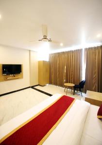 a hotel room with a bed and a tv at Hotel Ember in Alwar