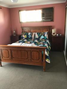 a bedroom with a wooden bed with a window at Villa on Ferguson in Ipswich +3 photos