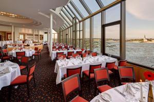 a dining room with white tables and chairs and windows at Hilton Mainz in Mainz