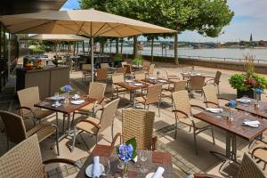 a restaurant with tables and chairs and a river at Hilton Mainz in Mainz +145 photos