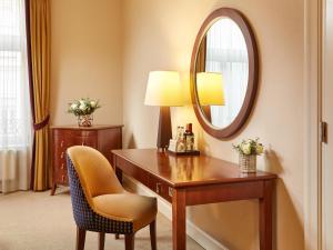a hotel room with a desk and a mirror at Corinthia Budapest in Budapest