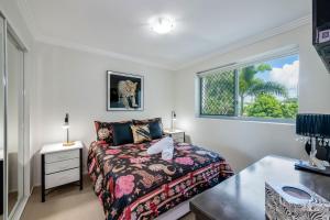 a bedroom with a bed and a desk and a window at Dwell Apartment 33 in Bargara