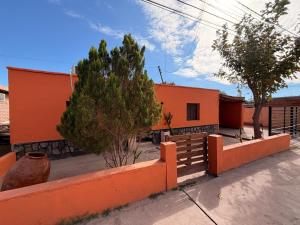 an orange house with a fence in front of it at Mis Montañas in Tinogasta