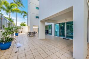 an outdoor patio with palm trees and a building at Dwell Apartment 33 in Bargara
