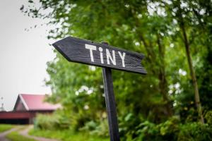 a black sign with the word tiny on it at Bostebacken Gard Tiny House by Tiny Away in Eckerud +21 photos