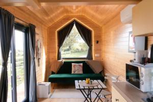 a living room with a green couch and a window at La Tiny Alchimiste by Tiny Away in Cressanges