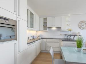 a kitchen with white cabinets and a blue table at Romanza - 0405 + park.38 in Middelkerke