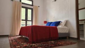 a bedroom with a bed with red and blue pillows at Suñu Tool Private Farm Guesthouse in Sindia