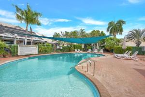 a swimming pool with a blue umbrella over it at Sunset Escape in Broome