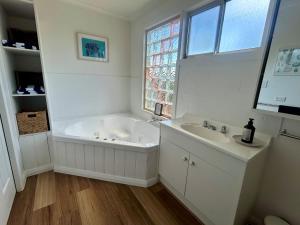 a bathroom with a tub and a sink and a window at Driftwood Cottage in Dolphin Sands