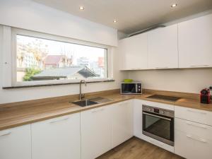 a kitchen with white cabinets and a window at Villa Tamarisk - + box in Middelkerke