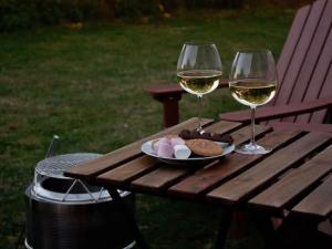 two glasses of wine and a plate of food on a picnic table at Sugar Hut by Tiny Away in Great Horkesley