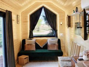 a green couch in a room with a window at Sugar Hut by Tiny Away in Great Horkesley