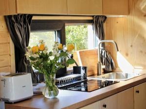 a vase of flowers on a counter in a kitchen at Vilasini Hut by Tiny Away in Great Horkesley