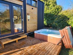a hot tub sitting on a wooden deck with a bench at Vilasini Hut by Tiny Away in Great Horkesley