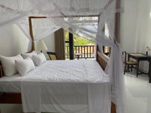 a bedroom with a white bed with a canopy at Ocean Crest Apartments in Mihiripenne