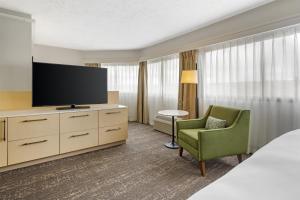 a hotel room with a television and a green chair at DoubleTree by Hilton Spokane City Center in Spokane