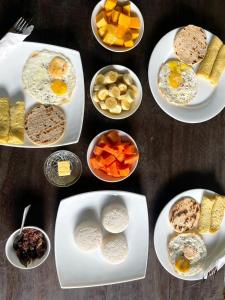 a table topped with plates of food with different foods at Rainforest Tea Garden Cabin-River View in Deniyaya