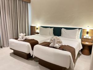 two beds in a hotel room with towels on them at Grand Luxcamp Pangandaran by Horison in Pangandaran +6 photos
