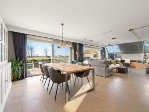a dining room and living room with a table and chairs at Maison Odille in Sint-Laureins
