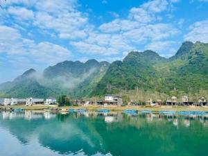 a village on the water with mountains in the background at Midtown homestay in Phong Nha
