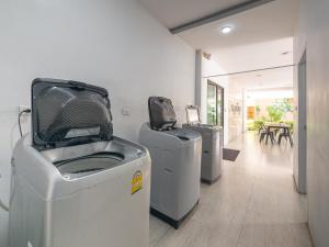 three washers and dryers are lined up in a room at Prukpibul Apartment in Bangkok