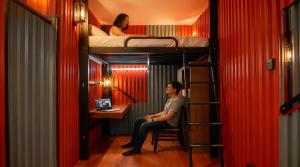 a man sitting in a chair in a room with bunk beds at hipstercity hostel in Singapore