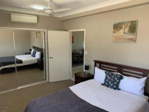 a bedroom with a large bed and a mirror at Modern Beach Apartment in Gladstone