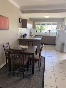 a kitchen with a table and chairs and a kitchen with a refrigerator at Modern Beach Apartment in Gladstone +12 photos