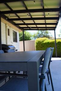 a table and chairs sitting under a patio umbrella at Yarrawonga Holiday House with Open Fireplace in Yarrawonga +16 photos
