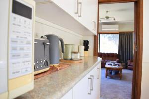 a kitchen with a stove top oven next to a living room at Yarrawonga Holiday House with Open Fireplace in Yarrawonga
