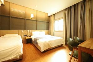 a hotel room with two beds and a desk at Ingye Joy Hotel in Suwon