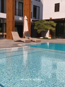 a swimming pool with two lounge chairs and an umbrella at Whale Retreat Destination in Hat Yai