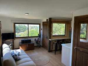 a living room with a couch and two windows at Cabañas y Lodges de Playa Ritoque RITOKAZO in Quintero