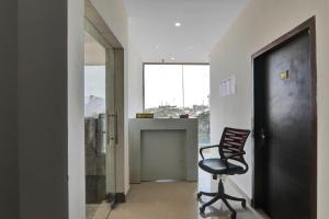 a black chair sitting in a hallway with a window at Hotel O Rudra Palace Near Phoenix United Lucknow in Alambagh