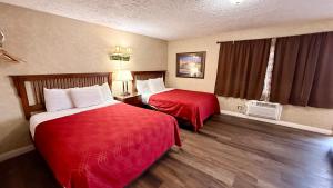 a hotel room with two beds with red sheets at Sage N Sand Motel in Moses Lake