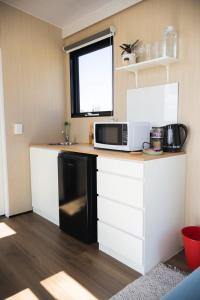 a kitchen with a black and white microwave on a counter at Beckford Tiny House 1 by Tiny Away in Good Hope